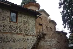 Каменните и тухлените стени на Боянската църква сред високите дървета